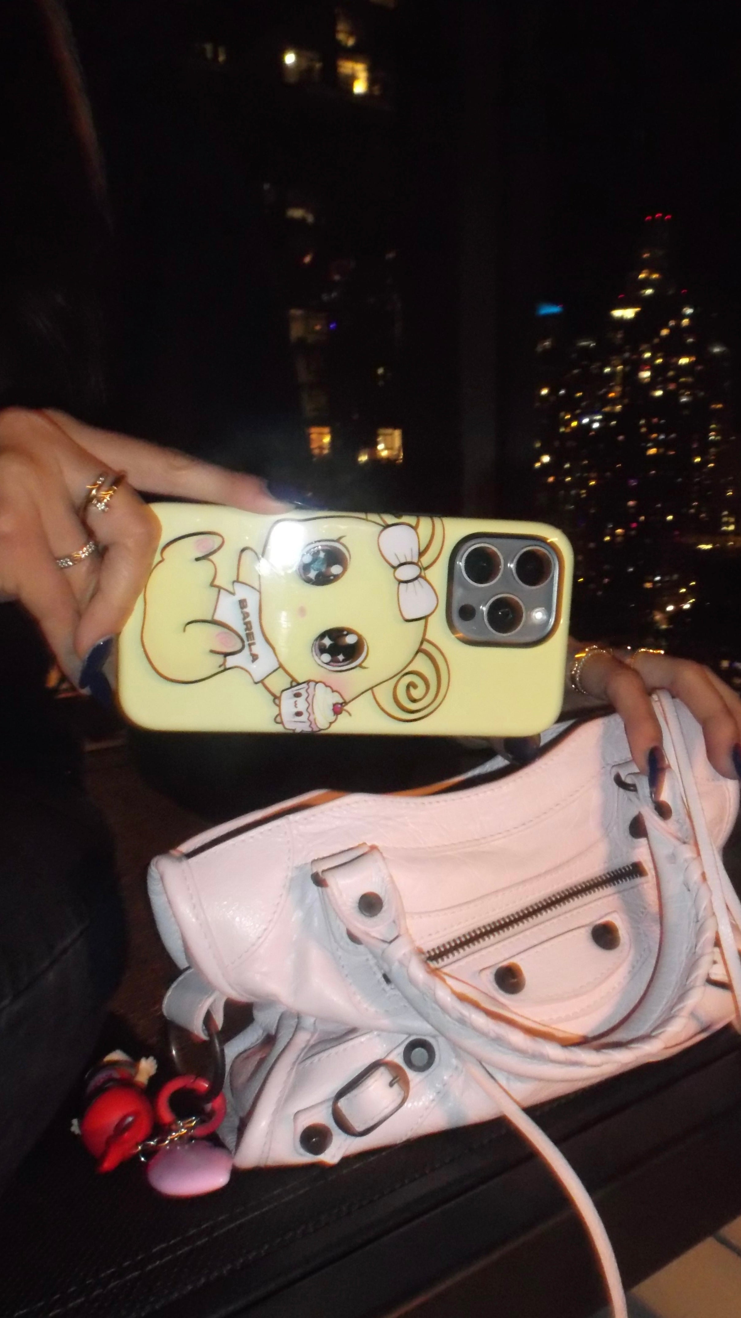 Phone case with cartoon design held up to camera, blurred cityscape in the background